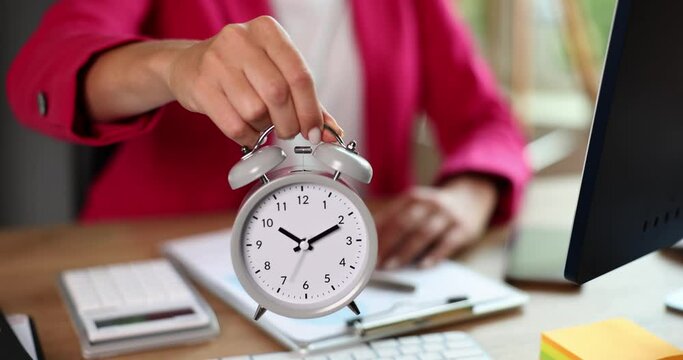 Businesswoman boss keeps an alarm clock at ten o'clock. Time management deadline and control of working time