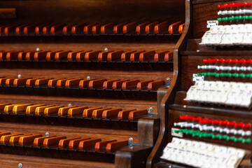 Naklejka premium Wooden keyboard of an antique church pipe organ. The photo was taken in the semi-darkness of the church interior