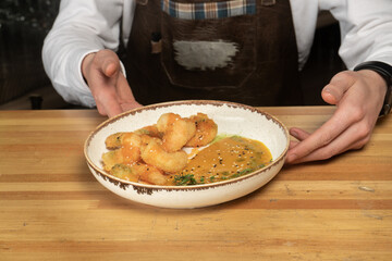 Shrimp in batter on a plate with sauce in the hands of a bartender