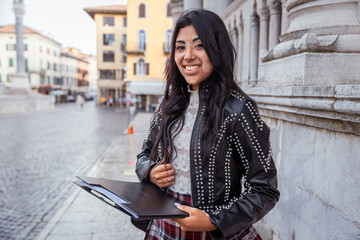 A young female student with vitiligo smiling is holding a folder