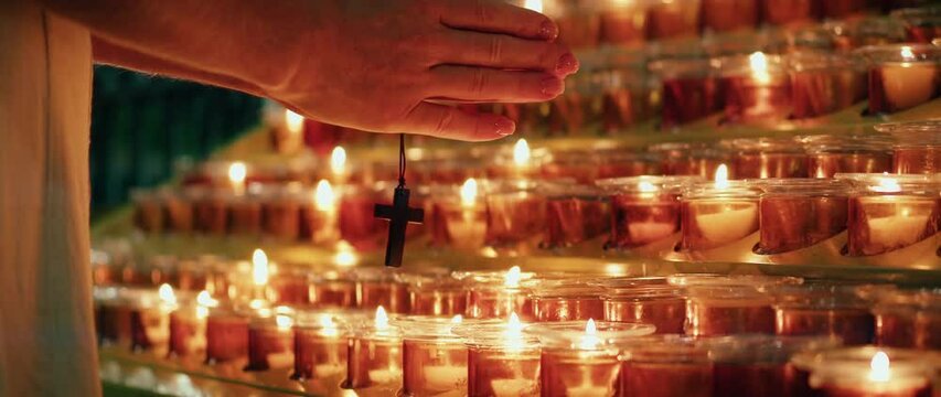 Woman praying near burning candles in church. Adult girl folded hands fervently atones for sins.