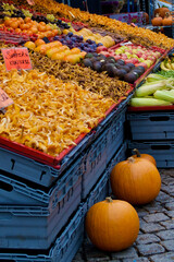 Close-up of a market stall with chanterelles and big pumpkins and other fruits and vegetables at farmers market in autumn.