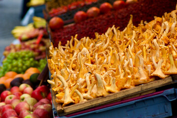 Close-up of a market stall with chanterelles and fruits and vegetables at farmers market in autumn.