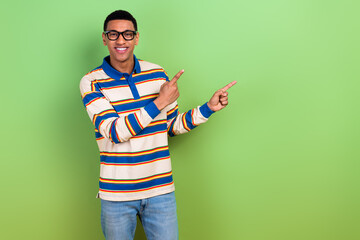 Photo portrait of nice young male fingers introduce point empty space dressed stylish striped garment isolated on green color background