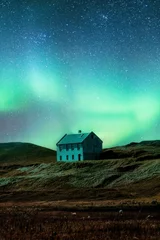Fotobehang Northern lights glowing over abandoned house on hill in remote location at Iceland © Mumemories