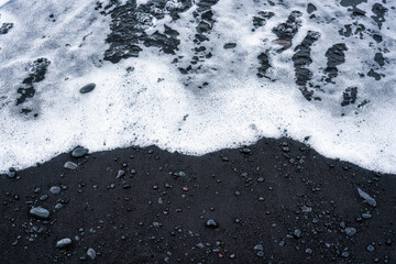 Sea wave on volcanic black sand beach in summer