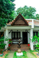 Modern Kerala style home with slanting roof made of clay tiles. Decorated with a tall lamp in the front yard.