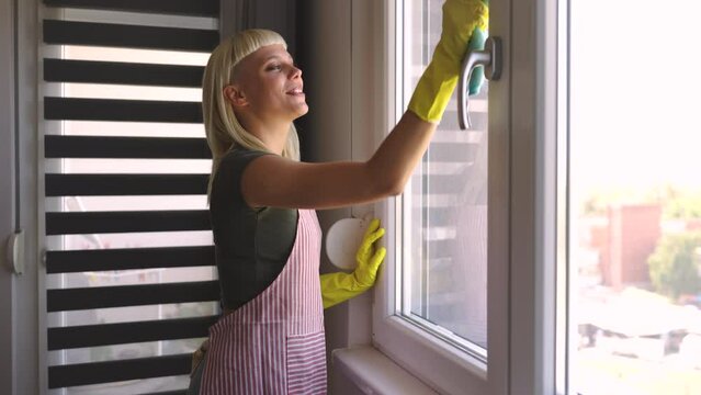 Young blonde woman cleaning windows