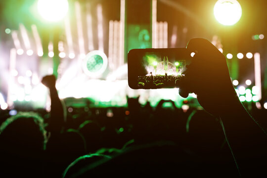 Taking a photo or video content at a music concert using a cell phone.