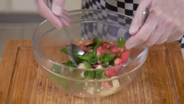 Mixing fresh vegetable salad with cuscus in a glass bowl