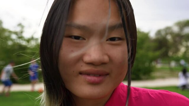 Young asian woman smiling on camera outdoor
