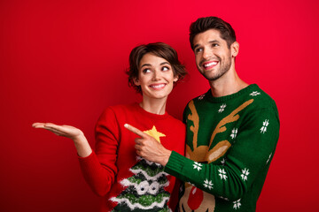 Photo of two funny positive people look direct finger hand hold empty space x-mas festive...