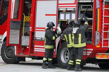 firefighters in action with the fire truck during the emergency with uniform and protective helmet