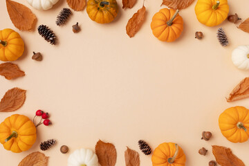 Autumn holiday frame from decorative pumpkins, dried foliage, berry, pinecones and acorns top view....