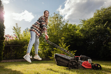 Happy female gardener working in autumn, cutting grass in backyard. Concept of gardening, work,...