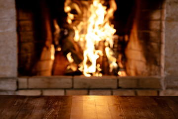 Empty old wooden table against burning wood in the fireplace