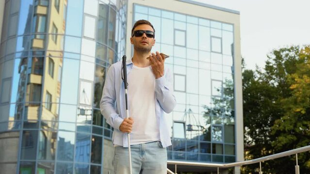 Young blind man speaks on the phone near business center
