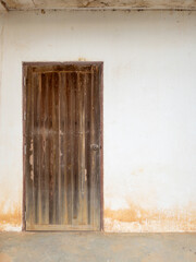 The old wooden door with the brass knob on the white wall.