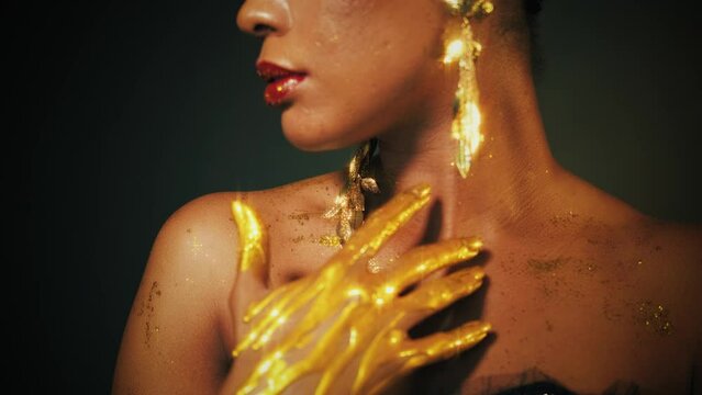 Portrait african woman fashion model beauty face close up. Glamour luxury Sexy Girl perfect skin, evening holiday shiny makeup glitter lip gloss, long earrings hands in gold liquid paint, black studio