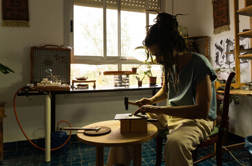 Young artisan working in a goldsmith workshop. Hammering piece for its elaboration.