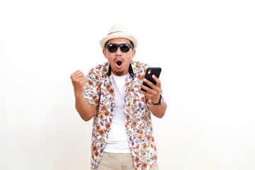 Excited happy adult Asian man tourist holding a cell phone while clenching hand. Concept of travel....