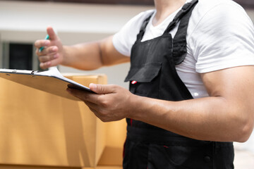 Unknown delivery men use clipboard checking cardboard box with shipping truck background	