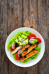 Caesar style salad - fried breaded chicken breast and vegetables on wooden table
