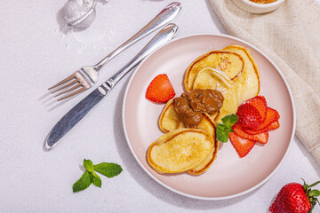 Cottage cheese pancakes, syrniki, curd fritters with strawberry, mint and powdered sugar on plate