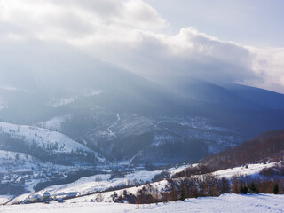 Fototapeta na wymiar mountainous carpathian countryside in winter. rolling landscape with snow covered hills. misty weather with clouds above the ridge