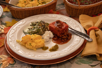 A plate with various side dished as part of a Plant Based Thanksgiving- mashed potatoes, green beans, corn bread, vegan curd, chili beans