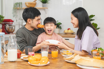 happy family together. Asian parent eating breakfast with little son in the kitchen. © Pormezz