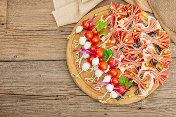 Set of picnic snacks on skewers. Jamon, mozzarella, cherry tomatoes, peas, fresh greens