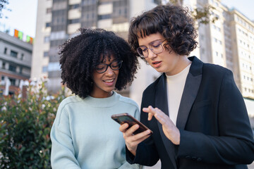 Two friends looking at smartphone in the street