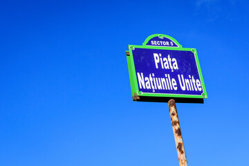 Beautiful vintage street sign showing Piata Natiunile Unite (United Nations Square) displayed on an street in the city center of Bucharest, Romania, in a sunny day with clear blue sky