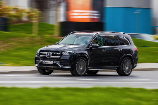 Black car Mercedes-Benz GLS 580 4MATIC X167 on the city road. Premium SUV fast driving on road in the city with blurred background