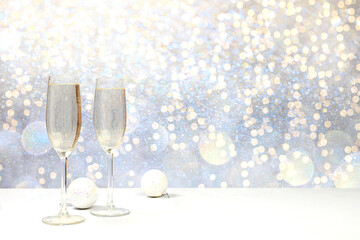 Two glasses of champagne on an elegant festive background with bokeh. Christmas and New Year layout for design and product display, Christmas Eve concept,