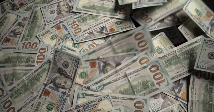 Bunch of dollar bills blows off table. One hundred dollar bills 100 usd money cash on dark wooden table blown away by wind. Bankruptcy insolvency business finance crisis failure crash concept.