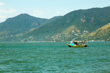 Barcos navegando em mar calmo, céu azul, dia de sol e montanhas ao fundo. São Sebastião, Litoral...