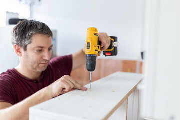 Man with electrical screwdriver. Kitchen assembly concept.