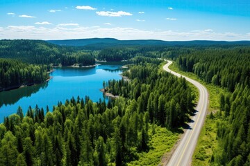 Fototapeta na wymiar Summertime Aerial View, Featuring Road Flanked By Lush Forest And Turquoise Lake