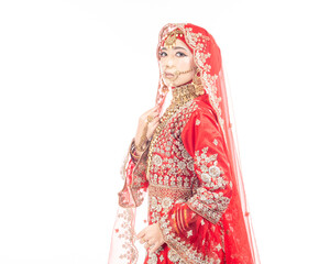 Close up portrait of a beautiful Asian Muslim lady in a hijab wearing a gorgeous Bollywood or Indian themed red traditional wedding dress isolated on white background