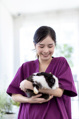 Woman holding cute fluffy Bunny at home. Friendship with Easter Bunny. A beautiful young woman with...