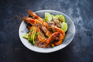 Traditional Thai fried king prawns with Asian vegetable, avocado slices and rice served as close-up on a design plate with text space