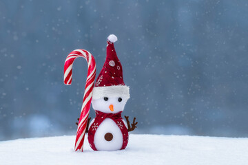 Christmas composition with a toy snowman on a snowy background.. Holiday concept for New Years cards.