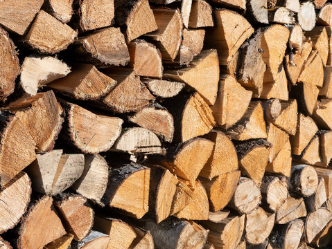 Woodpile lies in a heap, chopped for burning in a furnace. Finely chopped and stacked firewood, background. Laid dry firewood, texture, background. Firewood wall, dry chopped firewood background.