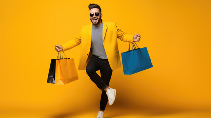 Happy smiling man holding shopping bags on yellow background - obrazy, fototapety, plakaty