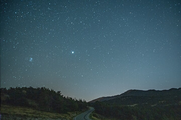 Ciel étoilé sur une route de montagne avec Jupiter et M45
