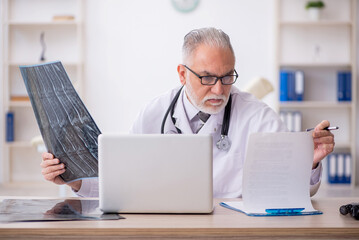 Old male doctor radiologist working in the clinic