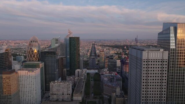 Aerial footage of metropolis at dusk. Backwards reveal of modern skyscrapers in futuristic La Defense district. Paris, France