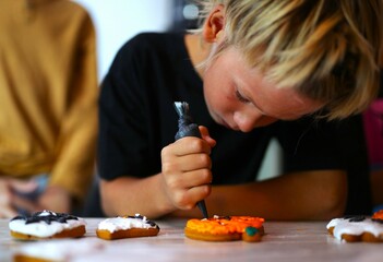 an eight-year-old boy is preparing for Halloween, the boy is painting gingerbread cookies, handmade, decorated place